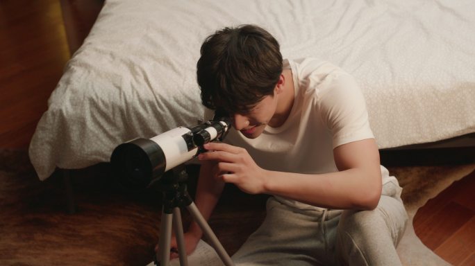 年轻男子在家使用望远镜
