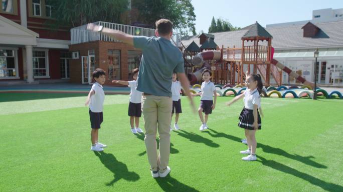 幼儿园外教和学生在操场做体操