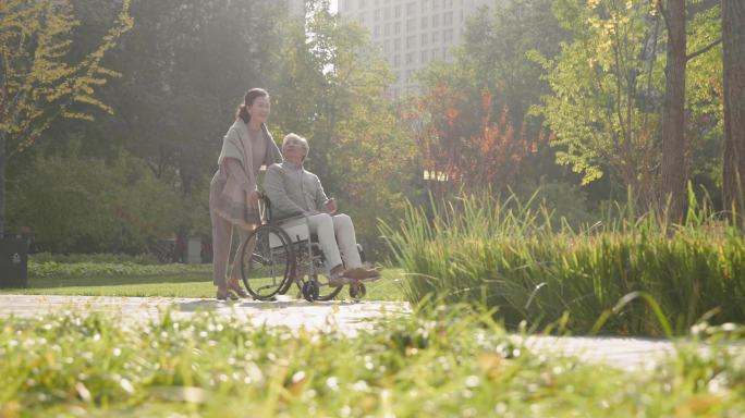 老人推着坐轮椅的老伴逛公园