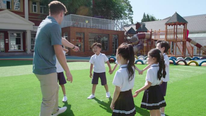 幼儿园外教和学生在操场玩耍