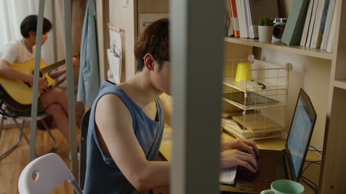 年轻大学生在宿舍使用笔记本电脑