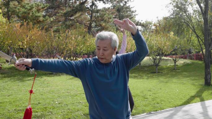 快乐的老年人在公园舞剑