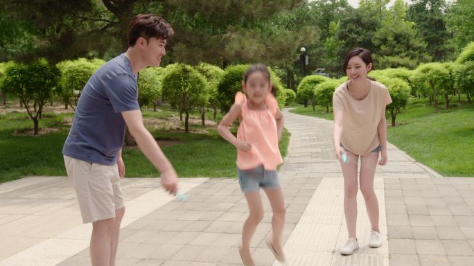 快乐的年轻家庭在公园跳绳