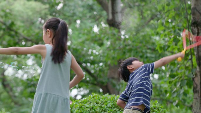 三个孩子在草地上吹泡泡