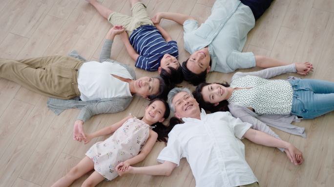 全家人躺在地板上一家人笑容笑脸陪伴父母孩