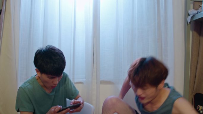 年轻大学生在宿舍玩手机游戏