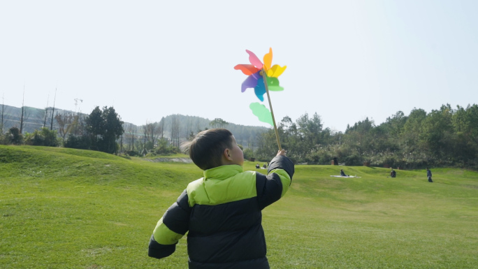 草地上小孩拿着风车奔跑户外玩耍美好时光