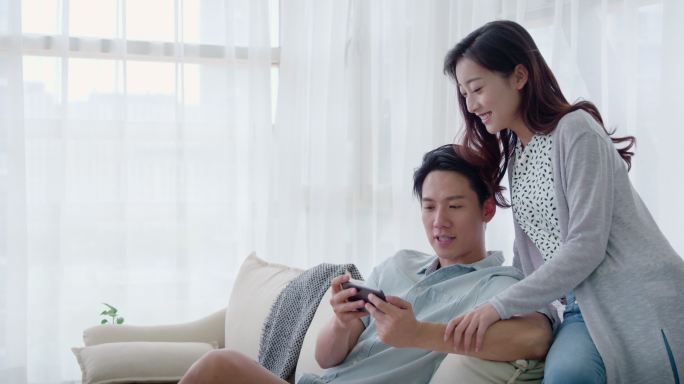 快乐的年轻情侣在客厅玩手机