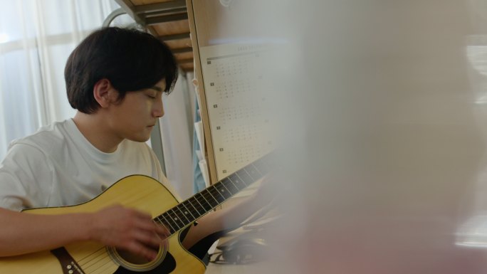 年轻大学生在宿舍弹吉他