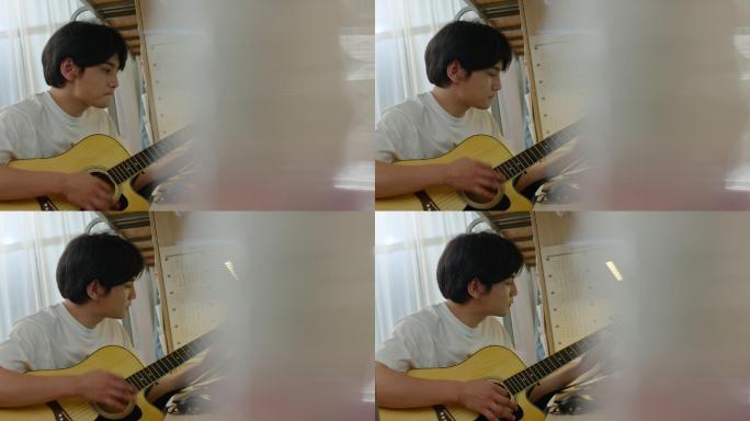 年轻大学生在宿舍弹吉他
