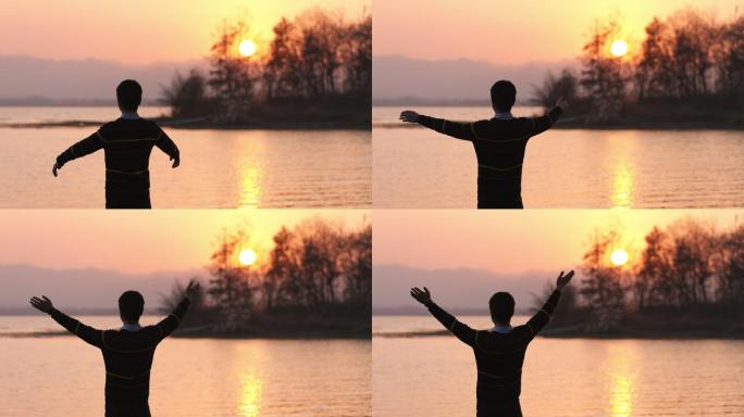 4K日落时分湖边的年轻男性举起双手