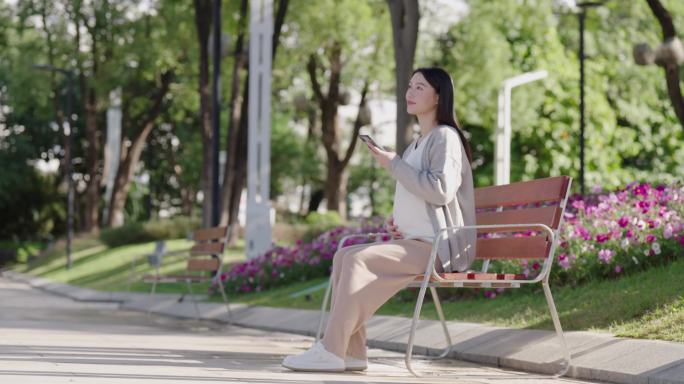 坐在长椅上的孕妇在玩手机