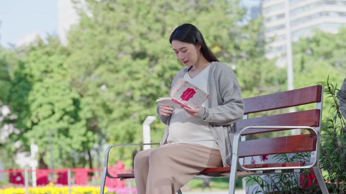 坐在长椅上看书的孕妇