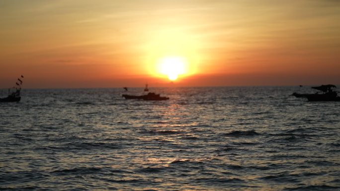 海边夕阳日落渔船和载冲锋艇的游客