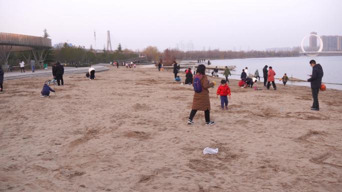家长带着小孩在公园湖面沙滩玩耍