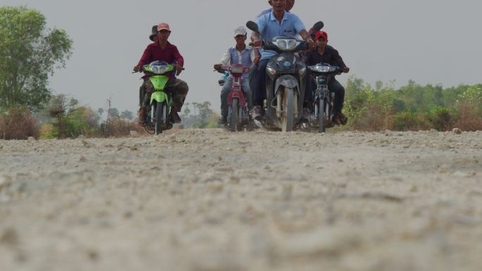 一群柬埔寨农民在土地驾驶摩托车