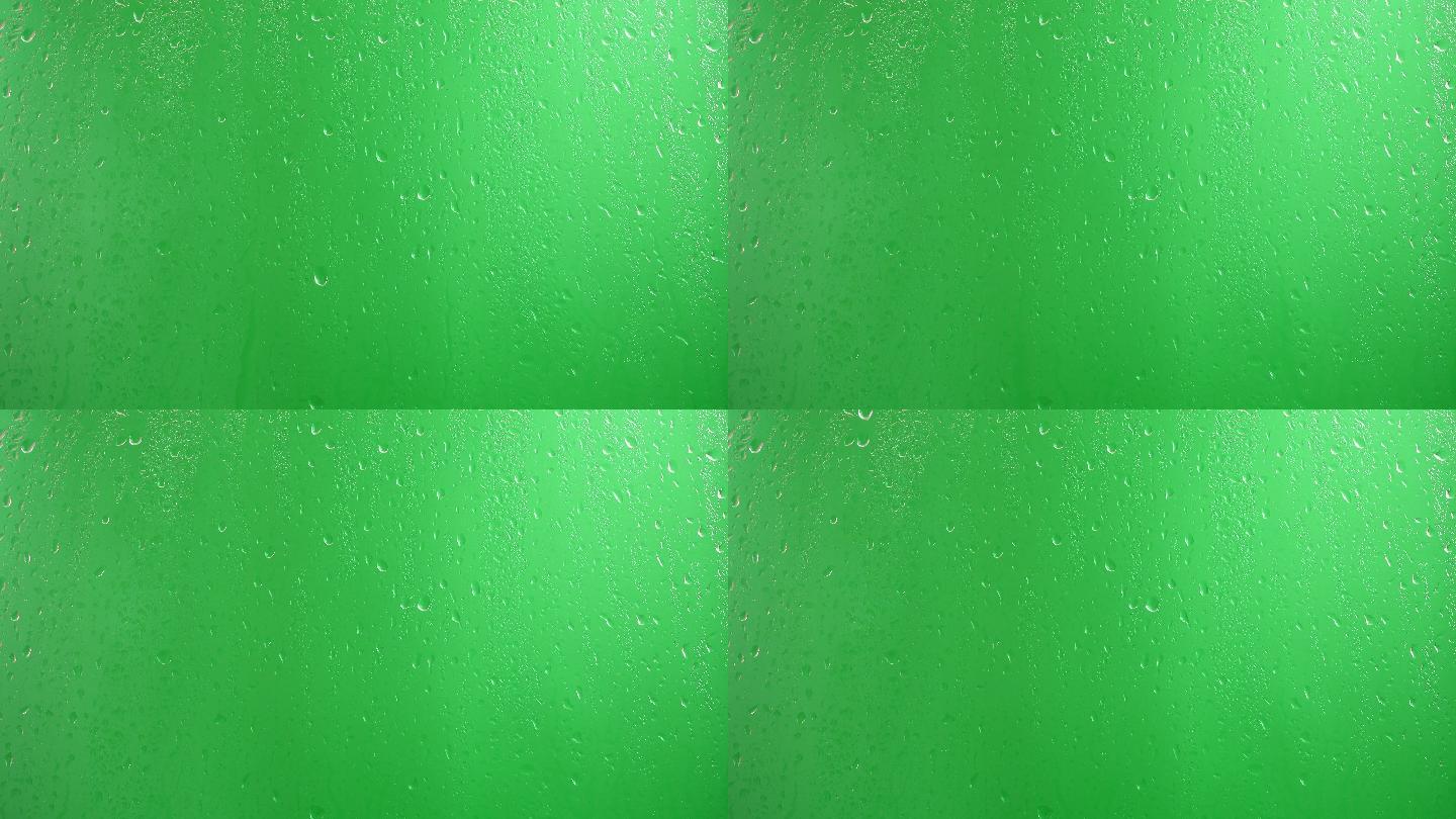 水滴沿着绿色背景的玻璃流下
