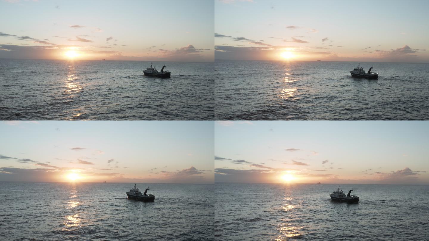 一艘拖网渔船在日落时横渡海洋