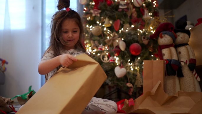 可爱的孩子在圣诞树下惊喜地拆开礼物