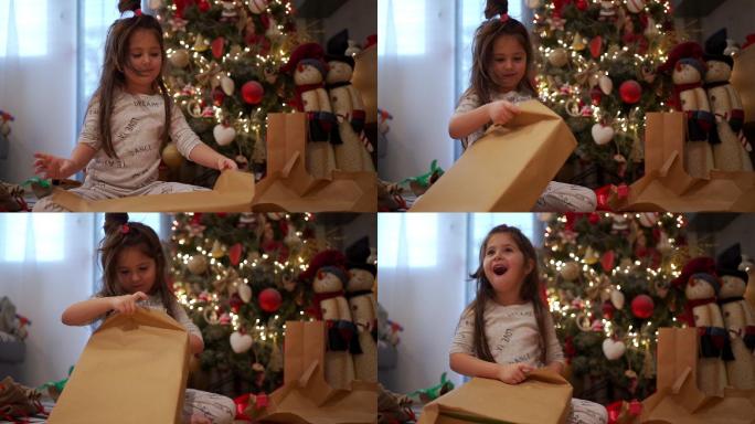可爱的孩子在圣诞树下惊喜地拆开礼物