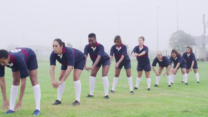 一组女子高中橄榄球运动员在球场上训练