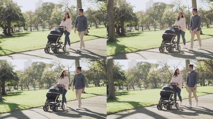 一个年轻家庭带着婴儿车在公园散步