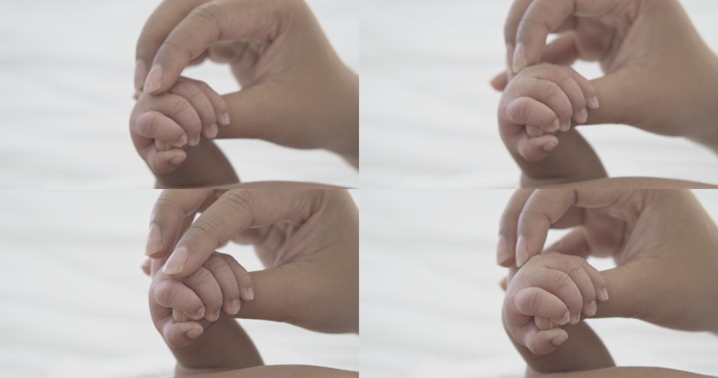 婴儿紧握着母亲的手指