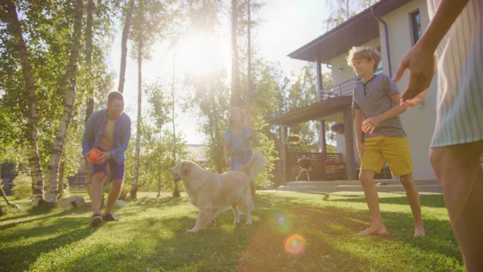 四口之家在后院的草坪上和快乐的金色猎犬玩