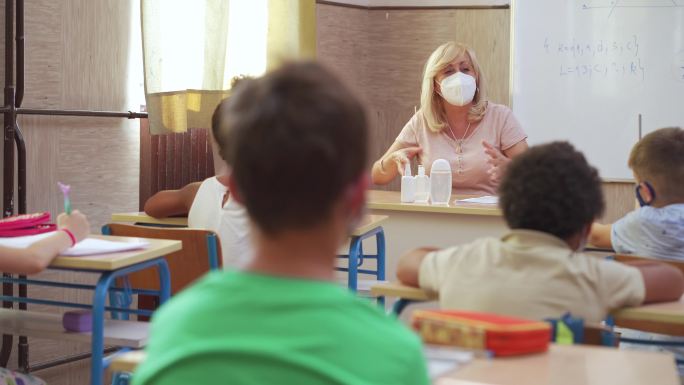 女教师和学童在教室戴着防护面罩
