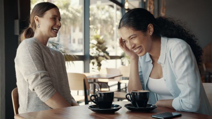 快乐的年轻女性朋友在咖啡馆见面