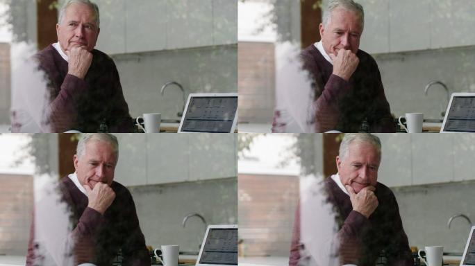 一位老人在家使用笔记本电脑时显得若有所思