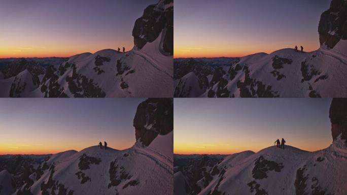 日出时，徒步旅行者在白雪覆盖的山脊上行走