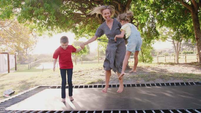 母亲和孩子们在蹦床上玩耍