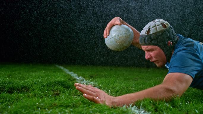 橄榄球运动员在倾盆大雨中带球倒地得分