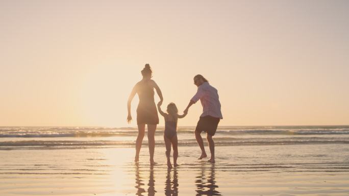 一个小女孩和她的父母在海边散步