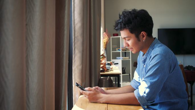 年轻帅哥在家里使用智能手机