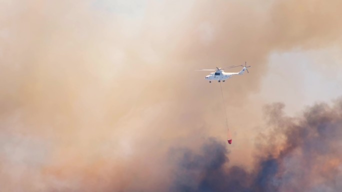 消防直升机救援飞机在行动中向火焰上喷水