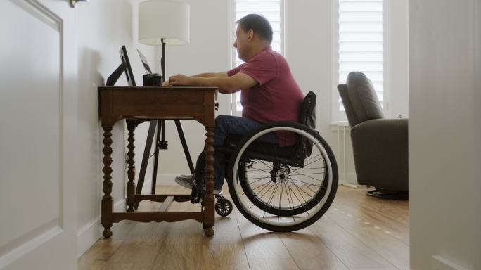 坐轮椅在家庭办公室工作的男人