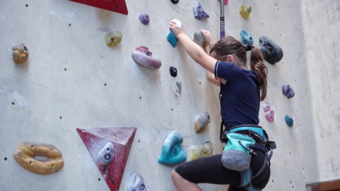 女孩在攀岩馆爬墙。
