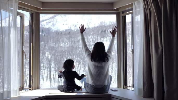 小男婴和妈妈坐在家里的窗台上