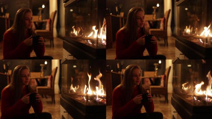 一个女孩在壁炉旁喝着一杯热巧克力咖啡