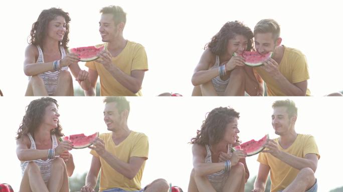 一对年轻夫妇在海滩上吃西瓜