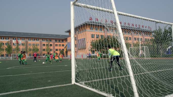小学生在操场踢足球训练练习