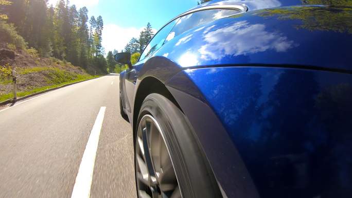蓝色跑车行驶在空旷蜿蜒的乡间道路上