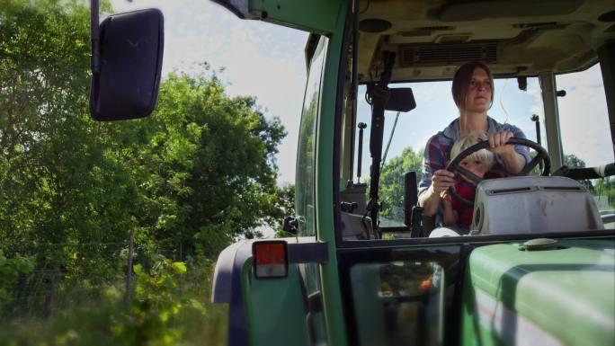 女农场主和她的儿子乘坐拖拉机穿过她的农场