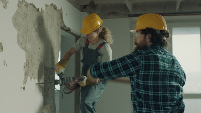 男女建筑工人一起拆墙