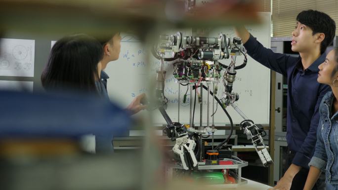 年轻的电子工程师团队在车间合作建造机器人。
