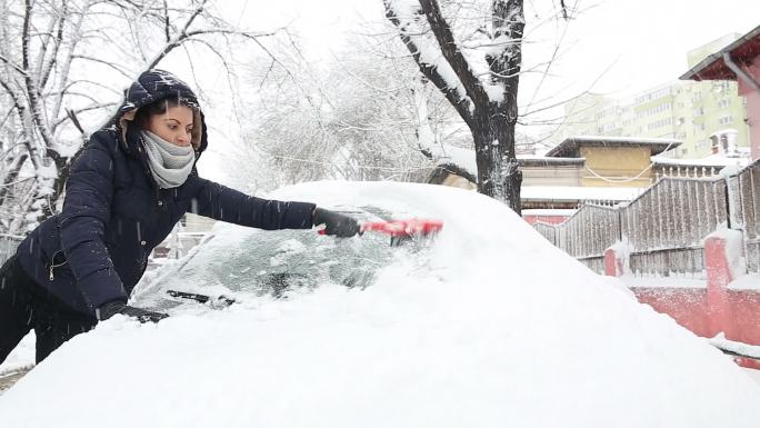 一位年轻女子正在刷去汽车上的积雪。