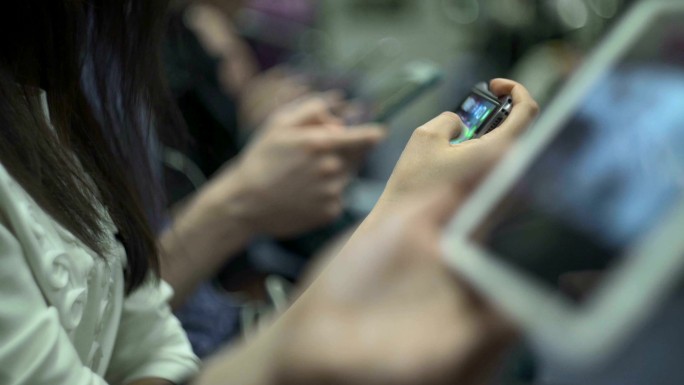 乘客在地铁列车上使用电子设备