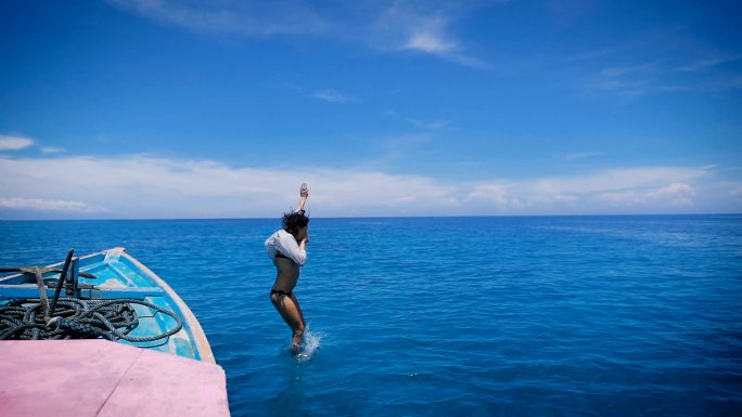 跳入海里的女人从船上跳下游泳潜水旅游避暑